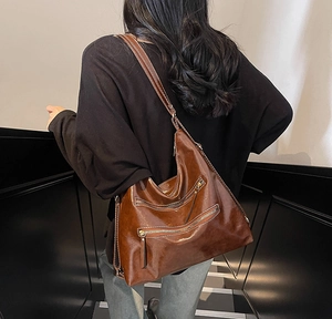 Détail du sac à bandoulière vintage en cuir huilé marron avec trois poches zippées