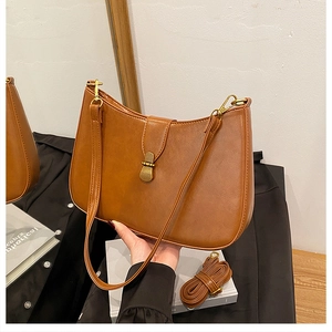 Detail view of brown leather crescent hobo bag with vintage buckle and extra strap