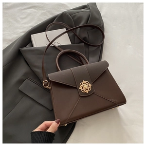 Detail of dark brown leather square bag featuring a gold petal-shaped clasp and texture