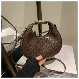 Macro detail of dark brown woven crescent bag with adjustable strap and metal lock