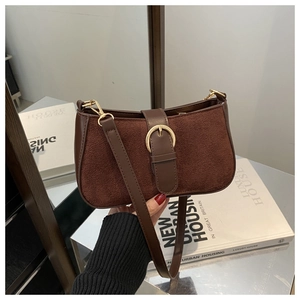 Detail of vintage brown leather underarm bag with gold buckle on a luxury magazine