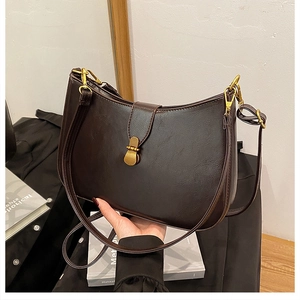 Close-up of brown oiled leather crescent bag with vintage gold clasp and fine texture