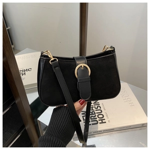 Detail of vintage black patchwork shoulder bag with elegant gold buckle and suede texture