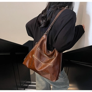Détail d'un sac bandoulière marron vintage avec plusieurs zips sur cuir synthétique poli