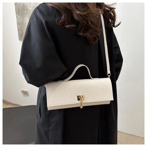 Detail of white crocodile pattern shoulder bag with golden buckle on a black coat
