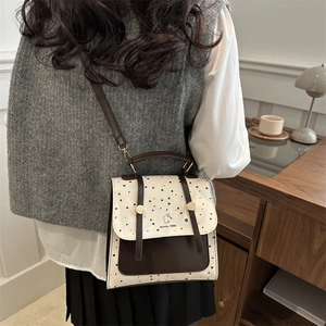Retro aesthetic backpack with cream polka dot flap and brown base on a wooden desk