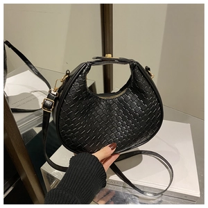 Detail view of black woven crescent bag with gold hardware and adjustable strap