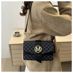 Detail of black underarm bag with M-letter monogram print and golden round buckle