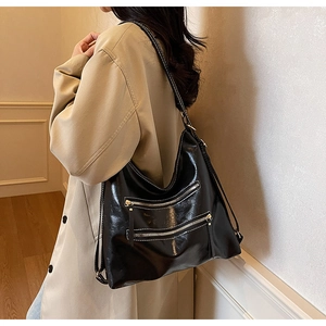 Détail du sac cabas en cuir noir brillant avec des poches zippées modernes multicouches
