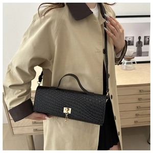 Detail of black woven texture handbag with golden clasp and tassel on a stylish model