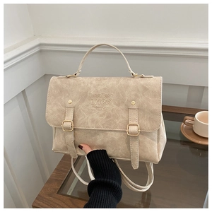 Détails de la serviette en similicuir beige avec boucles dorées et lettrage en relief