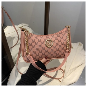 Close-up of pink crescent bag featuring metallic M logo and chain strap detail