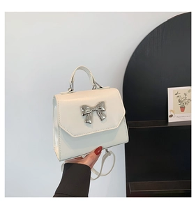 Détail d'un sac à main blanc avec boucle nœud en métal argenté et texture en cuir PU