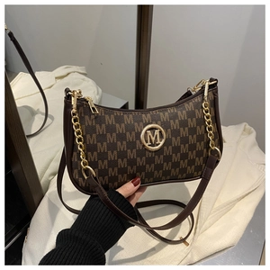 Detailed close-up of dark brown monogram crescent bag with golden M logo and chain