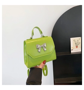 Détail d'un sac à main vert fluo avec un nœud en métal argenté et une poignée supérieure