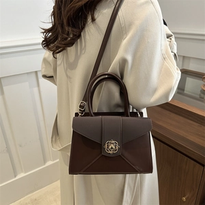 Retro dark brown crossbody square bag with gold buckle worn by model in beige coat