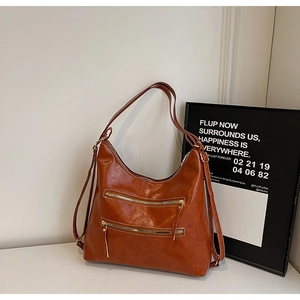 Détail du sac hobo marron avec doubles poches zippées et coutures contrastées blanches
