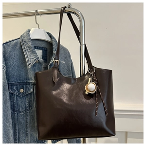 Λεπτομέρεια καφέ τσάντας από συνθετικό δέρμα με διακοσμητικό μπέιζμπολ και κορδόνι