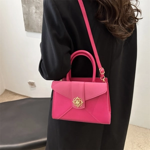 Rose pink leather crossbody bag with gold buckle worn on a black blazer jacket