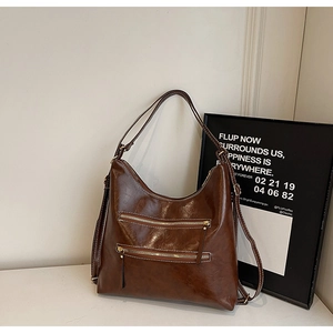 Détail du sac à bandoulière vintage en cuir huilé marron avec deux poches zippées en métal