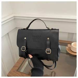 Détail du sac mallette vintage noir avec logo embossé et boucles métalliques décoratives
