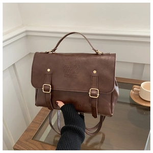 Vue détaillée du sac vintage marron foncé avec boucles dorées et texture en cuir gaufré