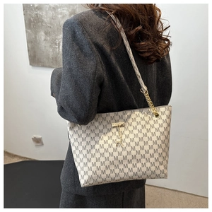 Detail of large tote bag showing grey M-letter pattern and chain shoulder strap