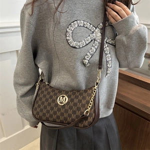 Sac croissant marron avec imprimé M et logo doré porté par un mannequin