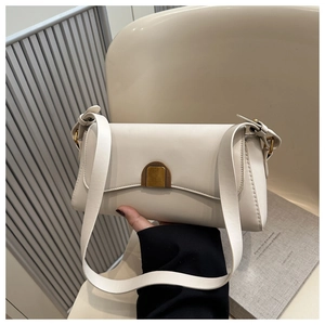 Detail of a creamy square shoulder bag featuring a vintage gold semicircular buckle closure