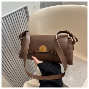 Detail of vintage brown faux leather baguette bag with antique gold buckle and wide strap