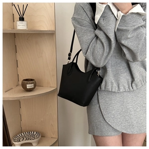 Detailed close-up of a minimalist black bucket bag with elegant wavy edge design
