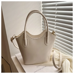 Detail view of cream bucket bag with wavy trim and textured matte leather surface