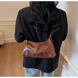 Dettaglio della borsa hobo in ecopelle marrone con rivetti retrò e finiture lucide