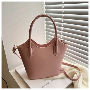 Close-up of pink bucket bag with wave-edge trim and adjustable strap on a window sill