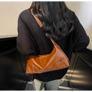 Dettaglio borsa hobo marrone vintage con borchie in metallo e trama in ecopelle lucida