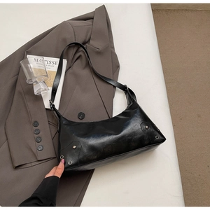 Dettaglio della pelle cerata con borchie argentate su una borsa sottobraccio nera