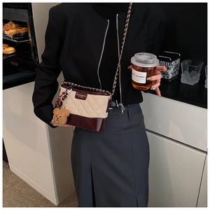 Détail du sac seau matelassé bicolore beige et bordeaux avec petit pendentif ours