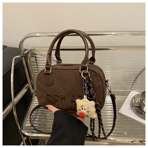 Detail der dunkelbraunen Wildleder-Bowlingtasche mit Logo und süßem Stern-Plüsch-Anhänger