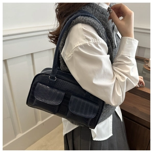 Detail of dark blue crocodile embossed handbag with double pockets and long handles