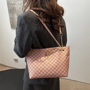 Rosa Tragetasche mit M-Muster und Goldhirsch-Anhänger an einem weiblichen Modell