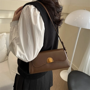 Minimalist dark brown leather shoulder bag with vintage gold buckle on a model