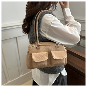 Detail view of beige crocodile embossed baguette bag with dual front flap pockets
