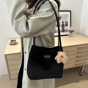 Sac seau élégant en peluche noire avec plaque logo dorée et breloque petit ours