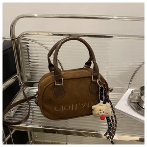Detailansicht der dunkelbraunen Wildledertasche mit Logostickerei und Bärenanhänger
