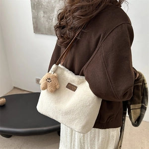 Sac seau en fausse fourrure blanche avec anses en cuir et charm ours porté par modèle