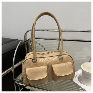 Detail of beige crocodile embossed tote bag with front pockets on a modern metal stand