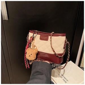 Détail du sac seau matelassé beige avec cuir rouge vin et chaîne dorée