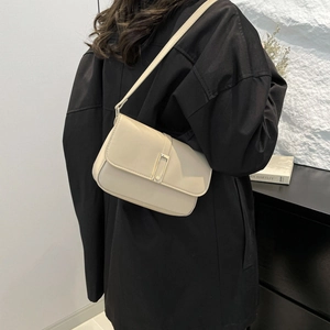 Minimalistische beige Leder-Schultertasche mit Metallschnalle getragen von einem Model