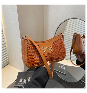 Detail showing mixed textures of brown crescent bag with golden butterfly buckle