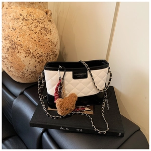 Détail d'un sac seau en cuir matelassé avec contraste noir et blanc et bandoulière chaîne